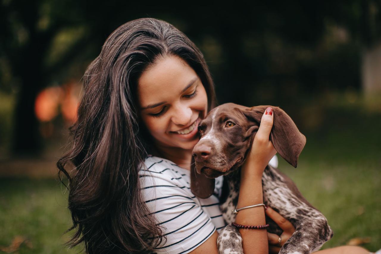 Mujer sonriente abrazando a su perro en un jardín