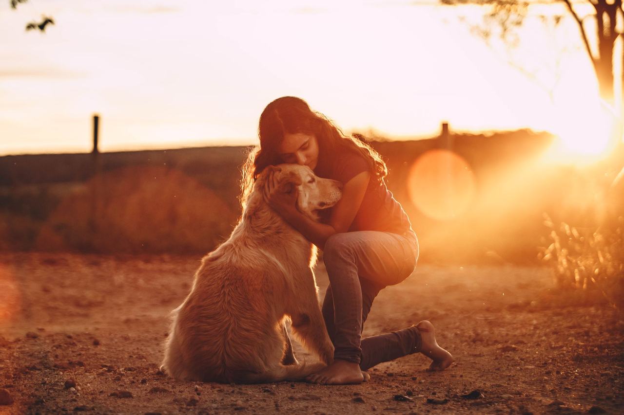Mujer abrazando a su perro al atardecer en el campo